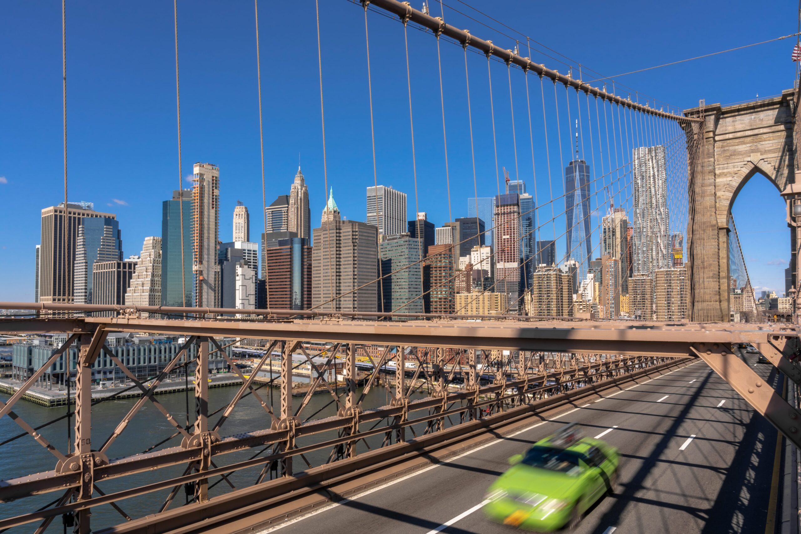 Car carrier delivering a sedan in New York City with skyline in background